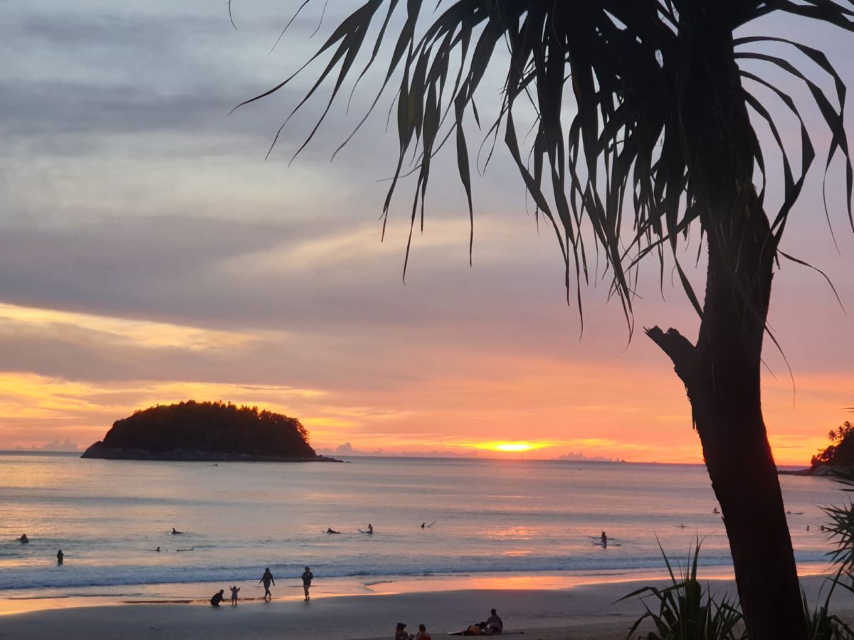Kata Beach in sunset Scenic view of Kata Beach with clear turquoise water, white sand, and palm trees in Phuket.