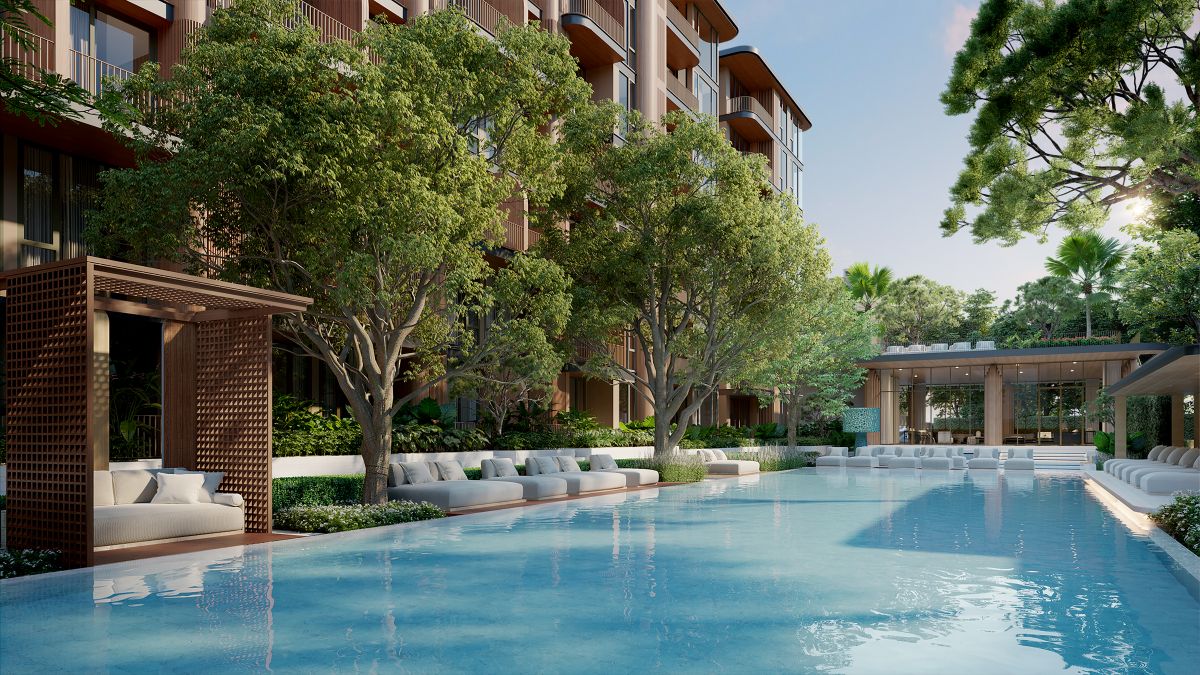 Resort-style swimming pool at Peylaa Phuket surrounded by lush tropical landscaping, sun loungers, and modern condo buildings in the background, creating a serene oasis near Bang Tao Beach.