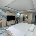 3-bedroom condo in Kamala, Phuket bedroom with light wood furniture and tv PSC-KAM-1604